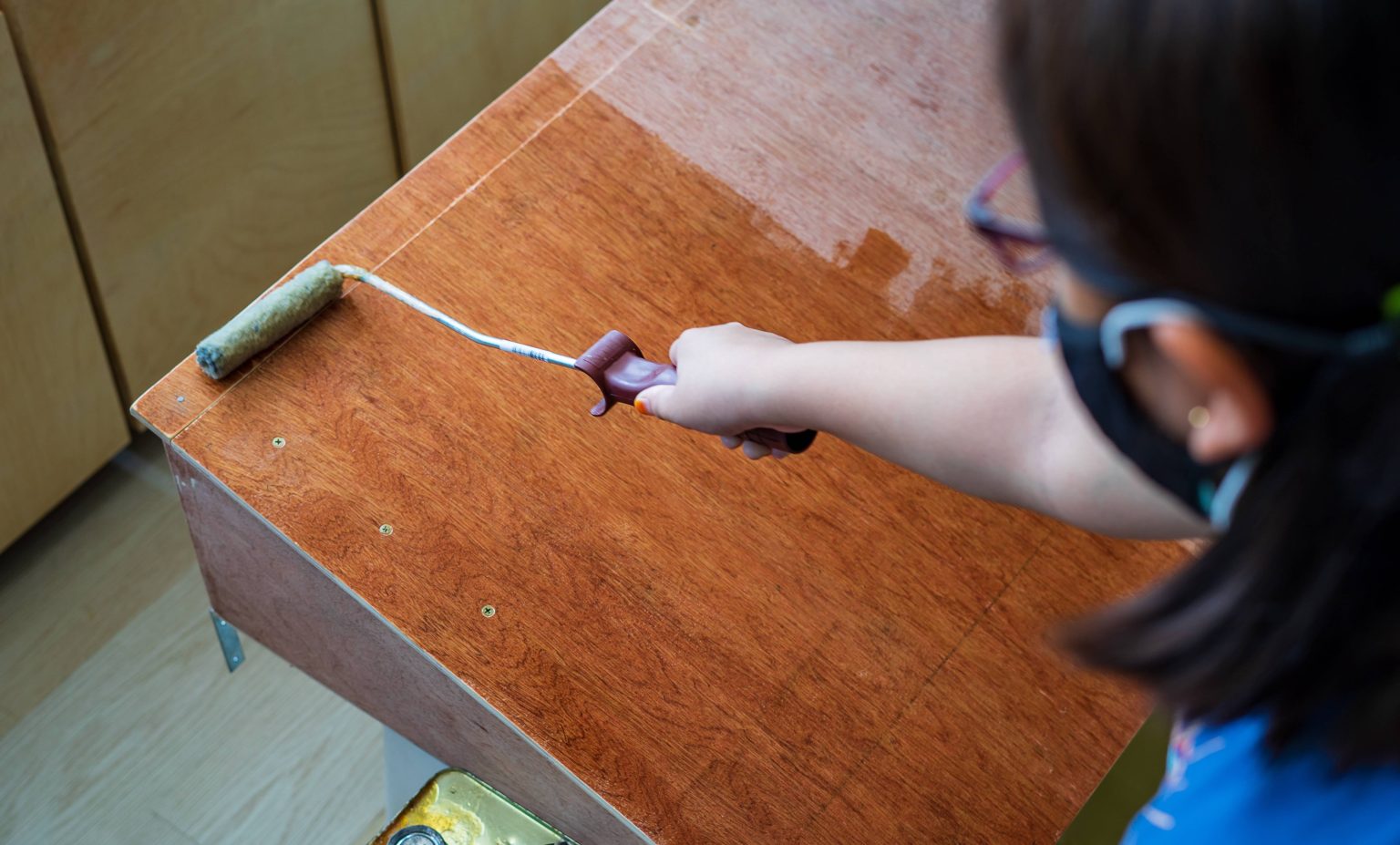 girl paints a board with a brush. Paint with gray paint. selective focus